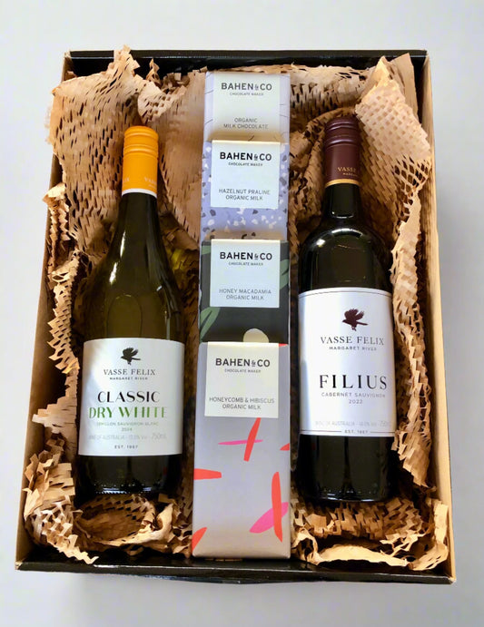 A hamper box containing two bottles of wine and chocolate bars with the Bahen & Co brand, presented as gifted wrapped items.