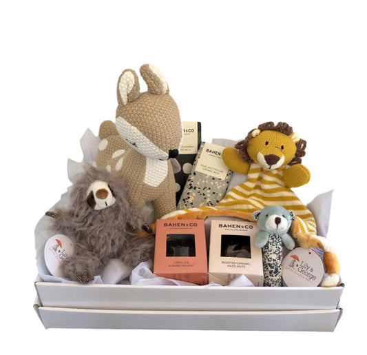 A baby gift hamper box containing soft toys, including a deer, sloth, and lion, along with packaged chocolates.