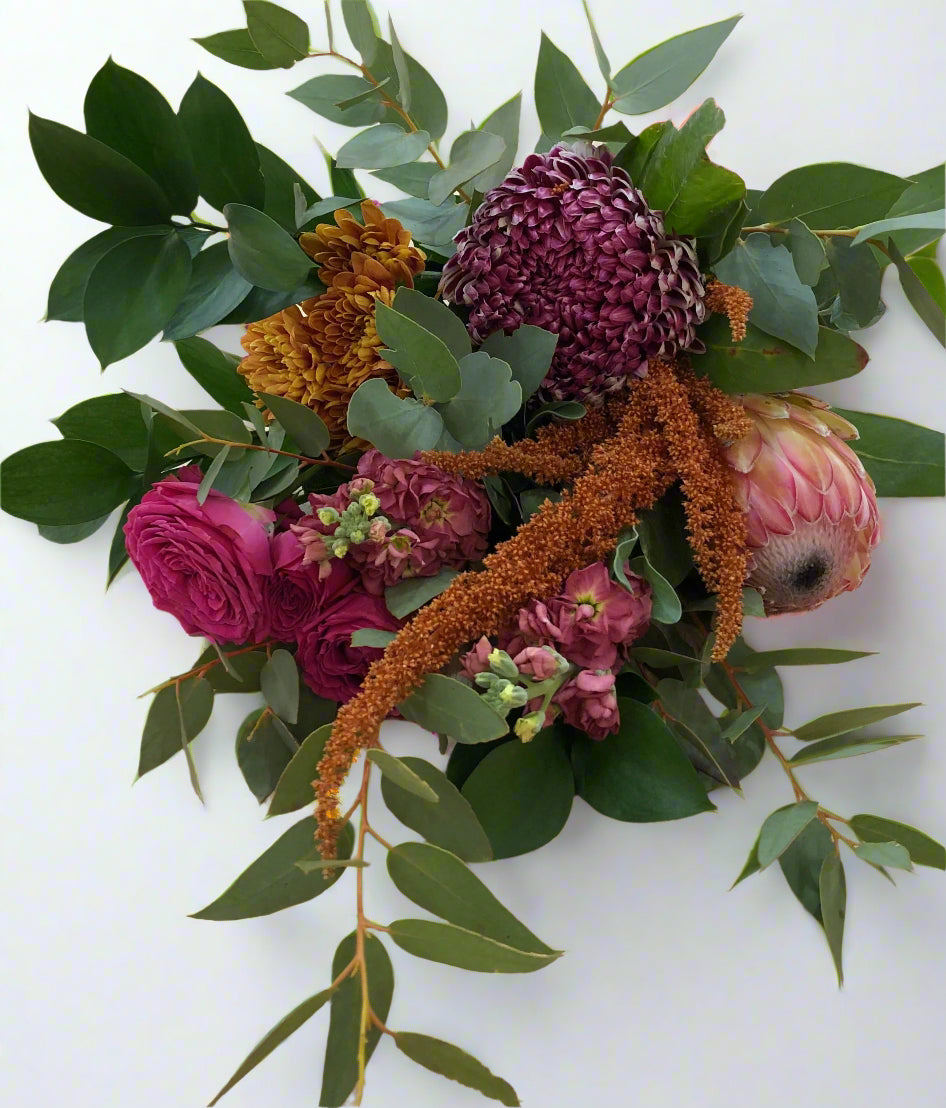 A floral arrangement with a selection of flowers in pinks, oranges, and greens, including text that reads 'warmth'.