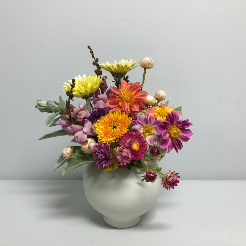 Colorful flower arrangement in a white vase on a light gray background