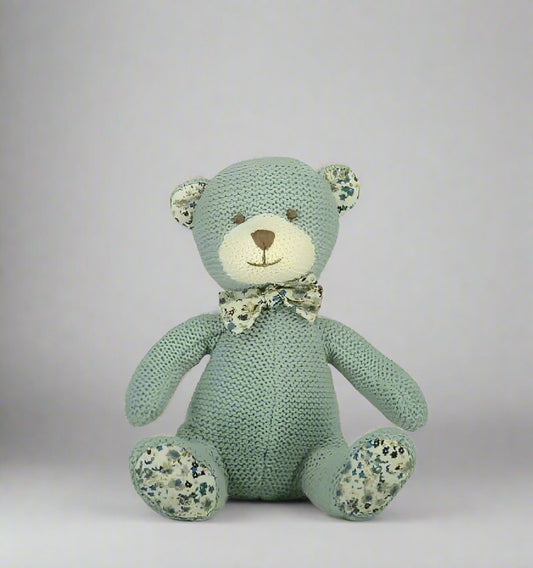 Knitted teddy bear with floral patterns on a gray background
