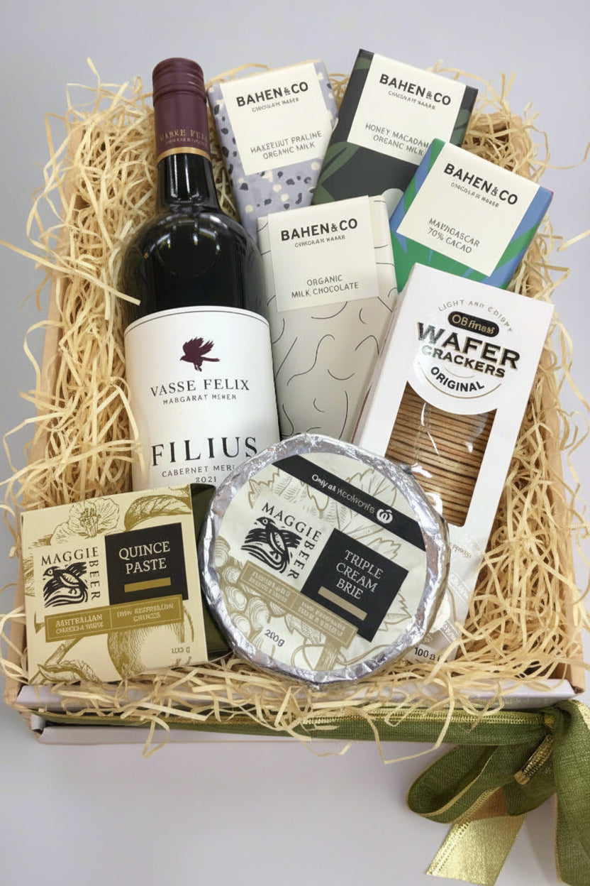 A gourmet hamper box containing assorted gourmet foods and beverages including a bottle of wine, chocolate bars, cheese, and crackers.