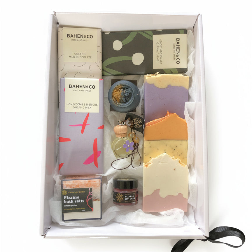 Gift set with various items including soap and chocolate in a box on a white background