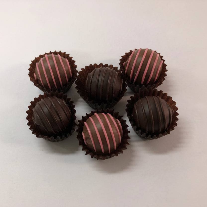 Chocolate truffles with pink stripes on a light background