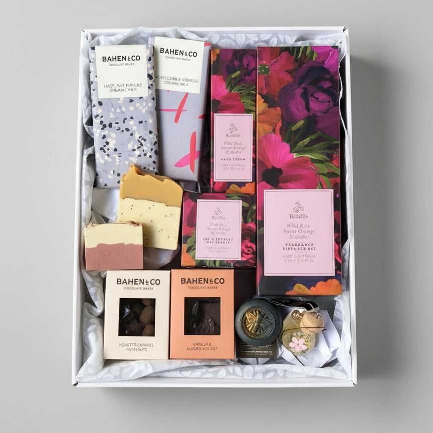 Gift set with various products including soap and candles in a box on a gray background