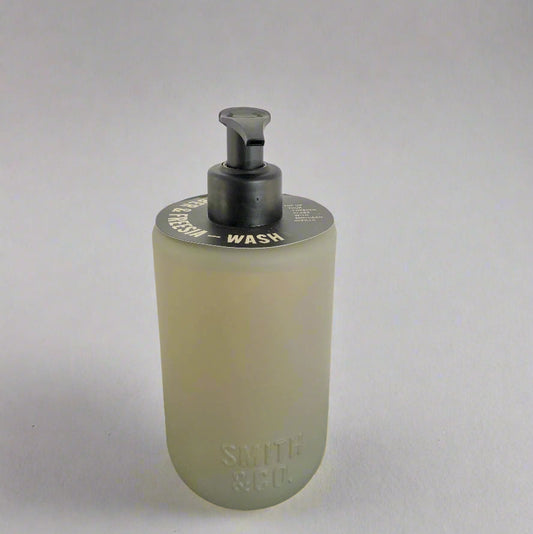 Foam soap dispenser with pump on a black surface against a white background