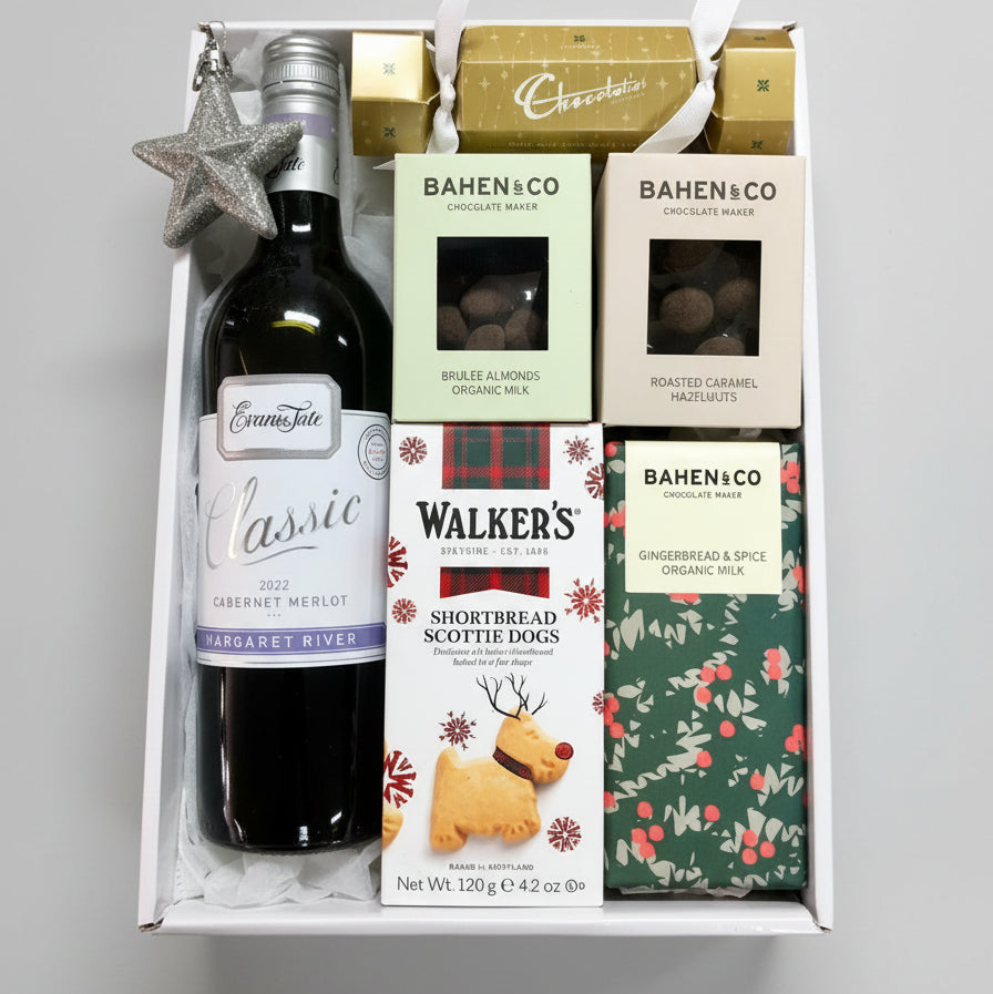 Gift basket with wine, chocolate, and shortbread on a wooden surface