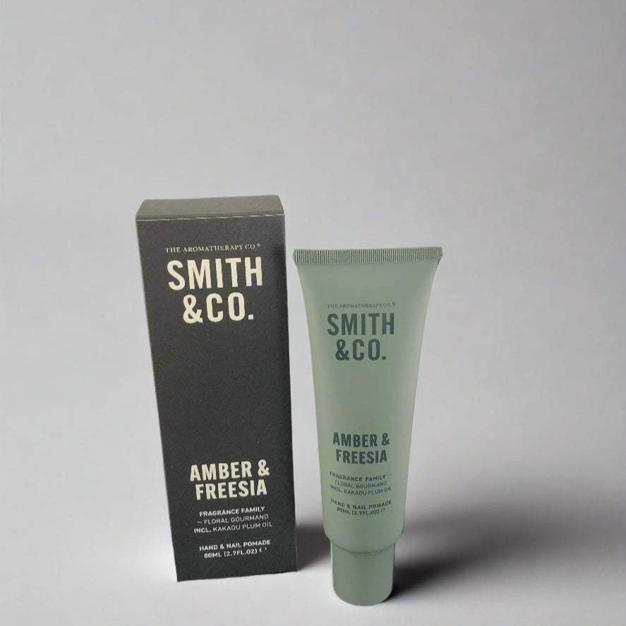 Smith & Co. amber & freesia product packaging on a black surface with a white background