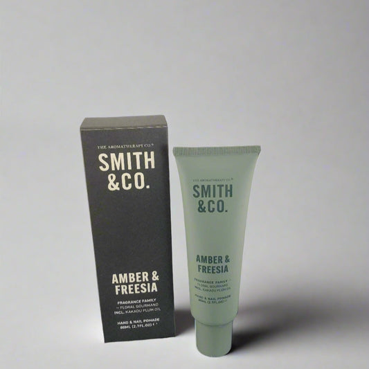Smith & Co. amber & freesia product packaging on a black surface with a white background