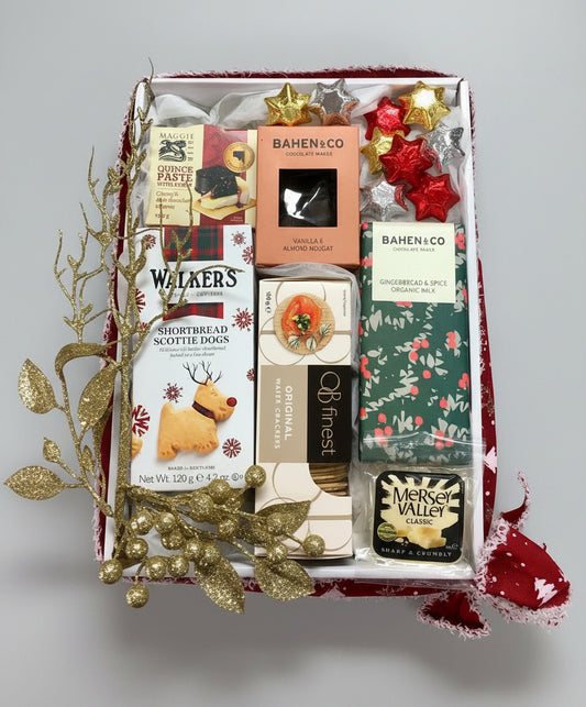 Gift box with various items including Walkers shortbread, Bahen & Co chocolates, and other treats on a wooden surface.