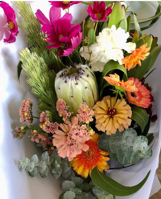 Bouquet of colorful flowers including pink, white, orange, and green on a white background