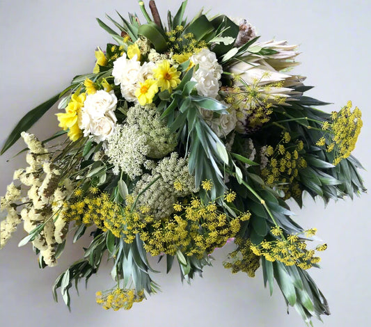 A bouquet of flowers featuring various yellow and white flowers with green foliage.