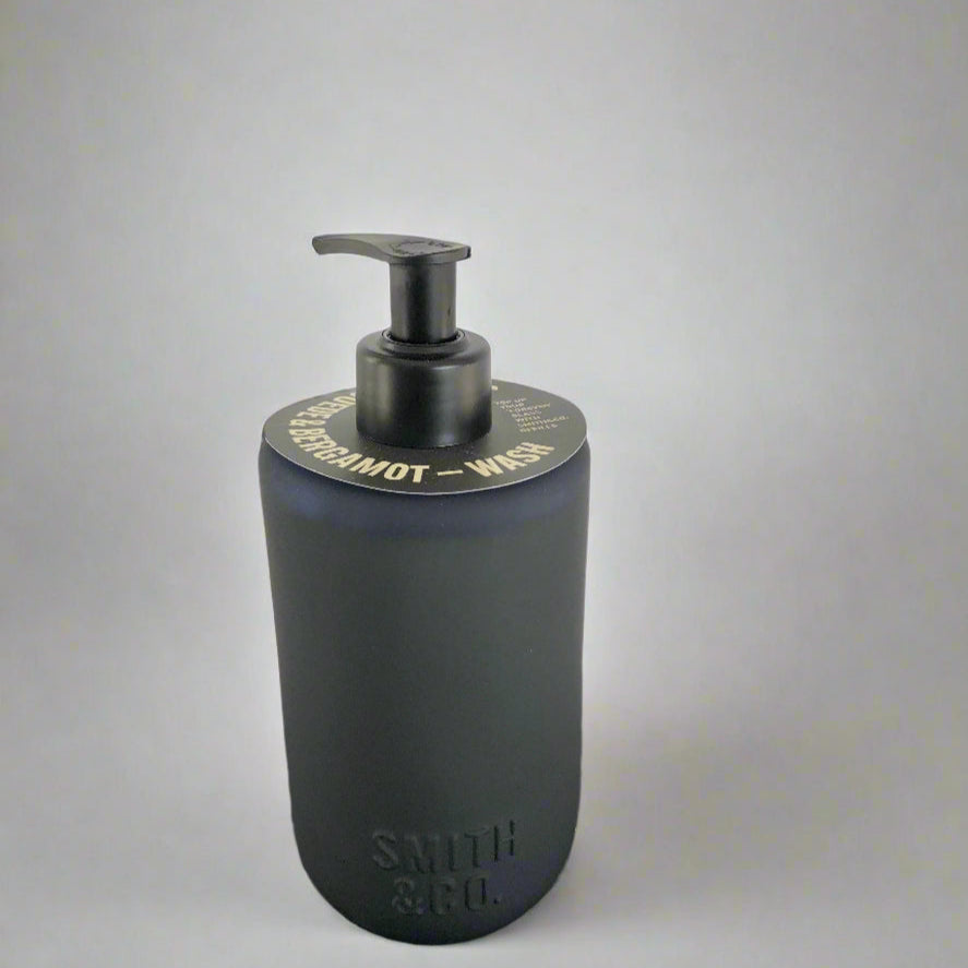 Dark blue soap dispenser with pump on a black surface against a white background