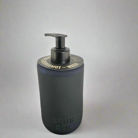 Dark blue soap dispenser with pump on a black surface against a white background