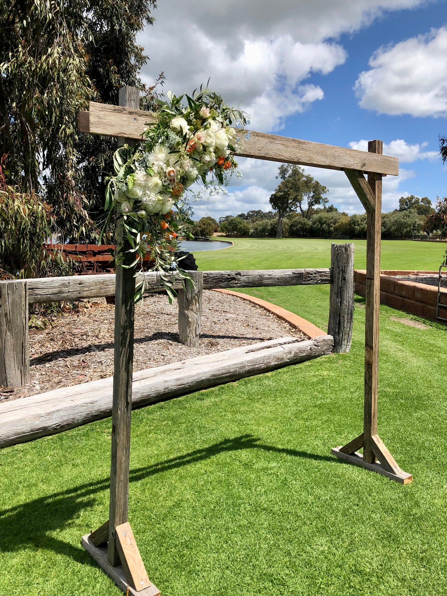 Wooden arch with floral decorations on a grassy field