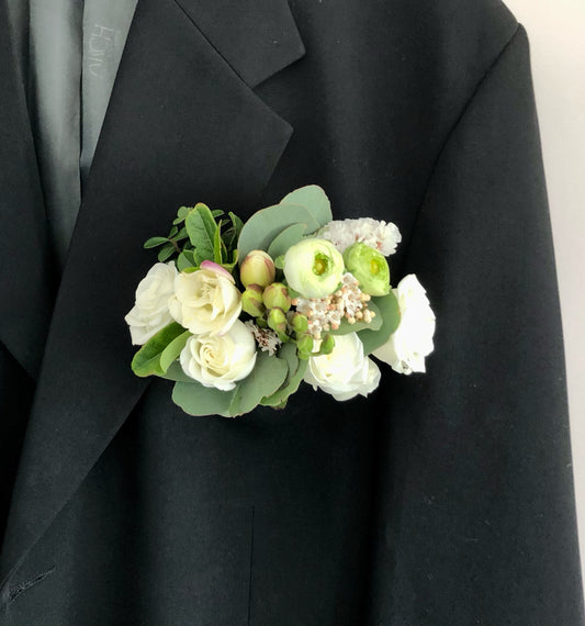 Floral corsage on a black suit jacket against a neutral background