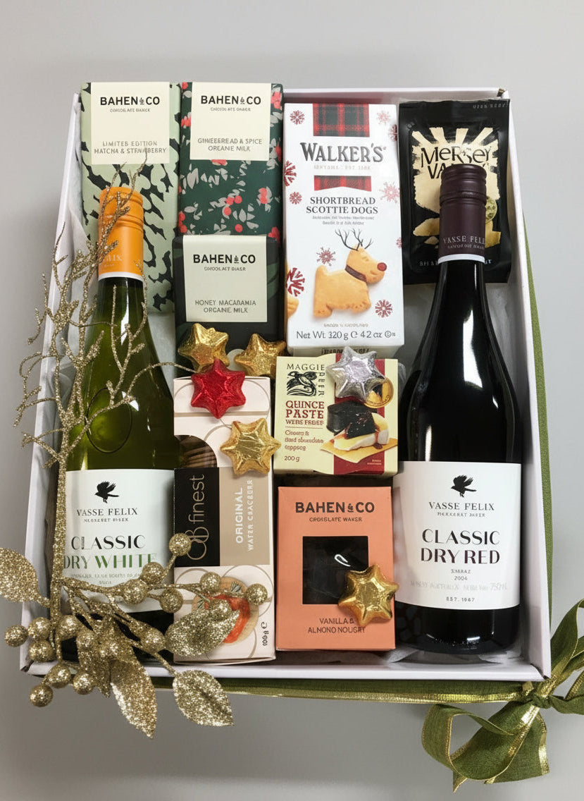 Gift box with wine bottles and assorted snacks on a wooden surface