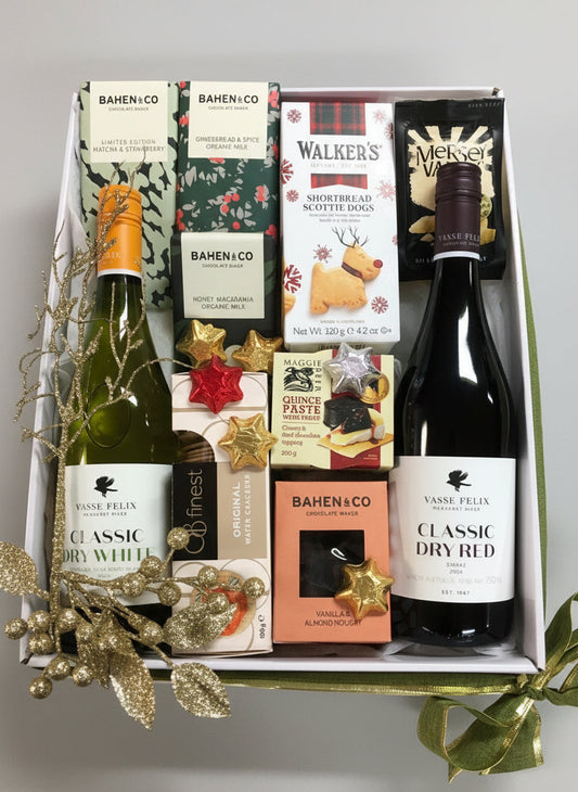 Gift box with wine bottles and assorted snacks on a wooden surface