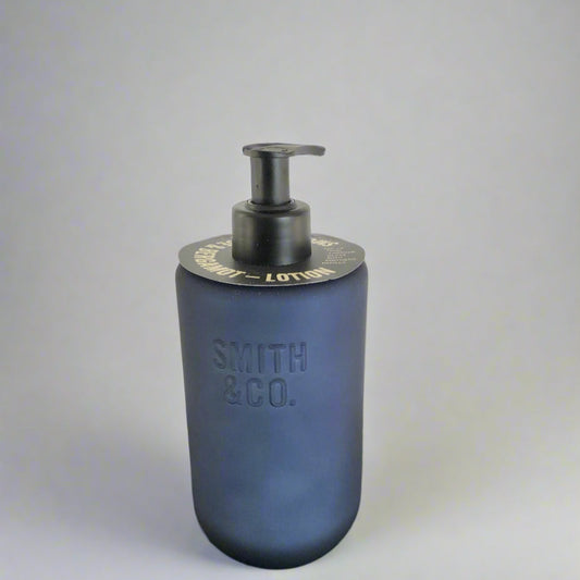 Blue soap dispenser with black pump on a dark surface and light background